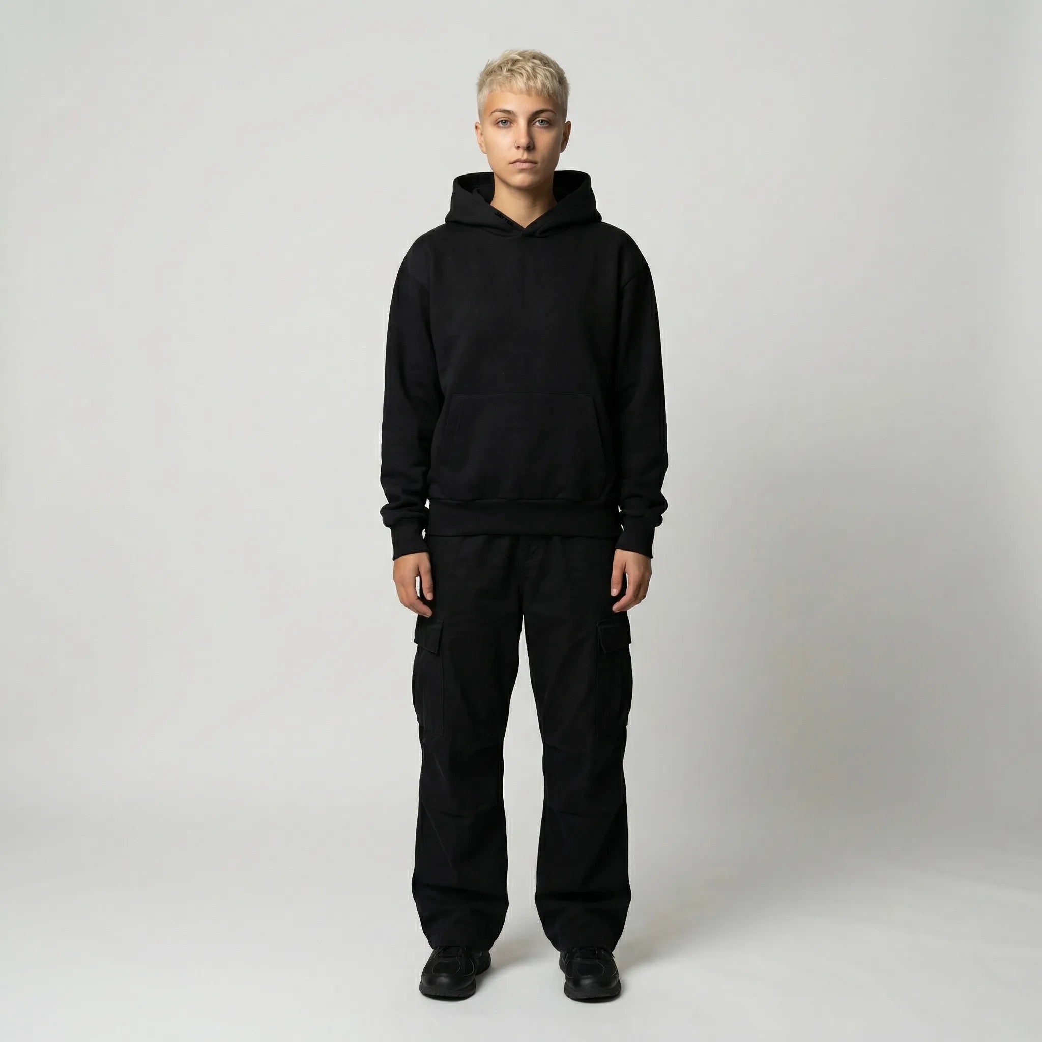 Person wearing a black hoodie and pants on a white background