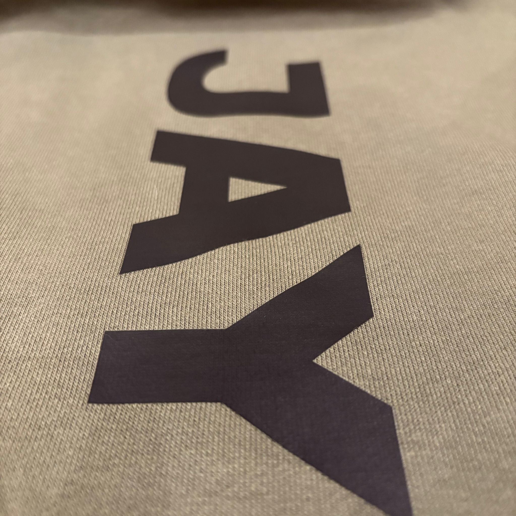 Start of JAYTEE logo printed on a green background