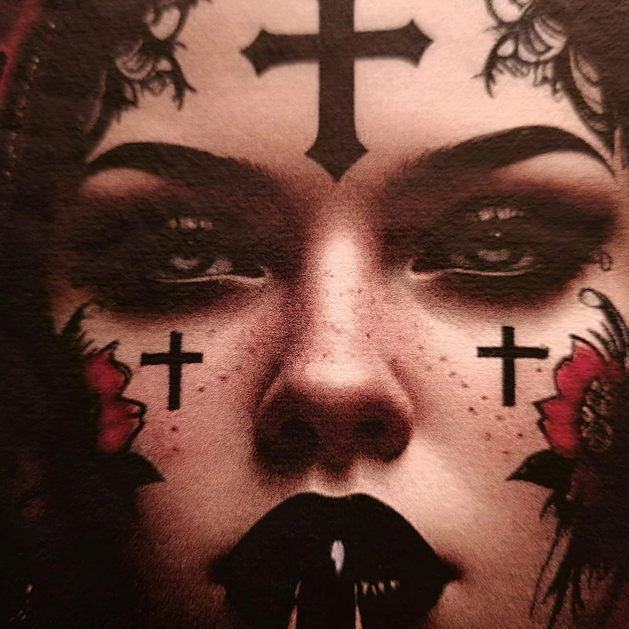 Close-up of a person's face with tattoos and makeup, including crosses and flowers.