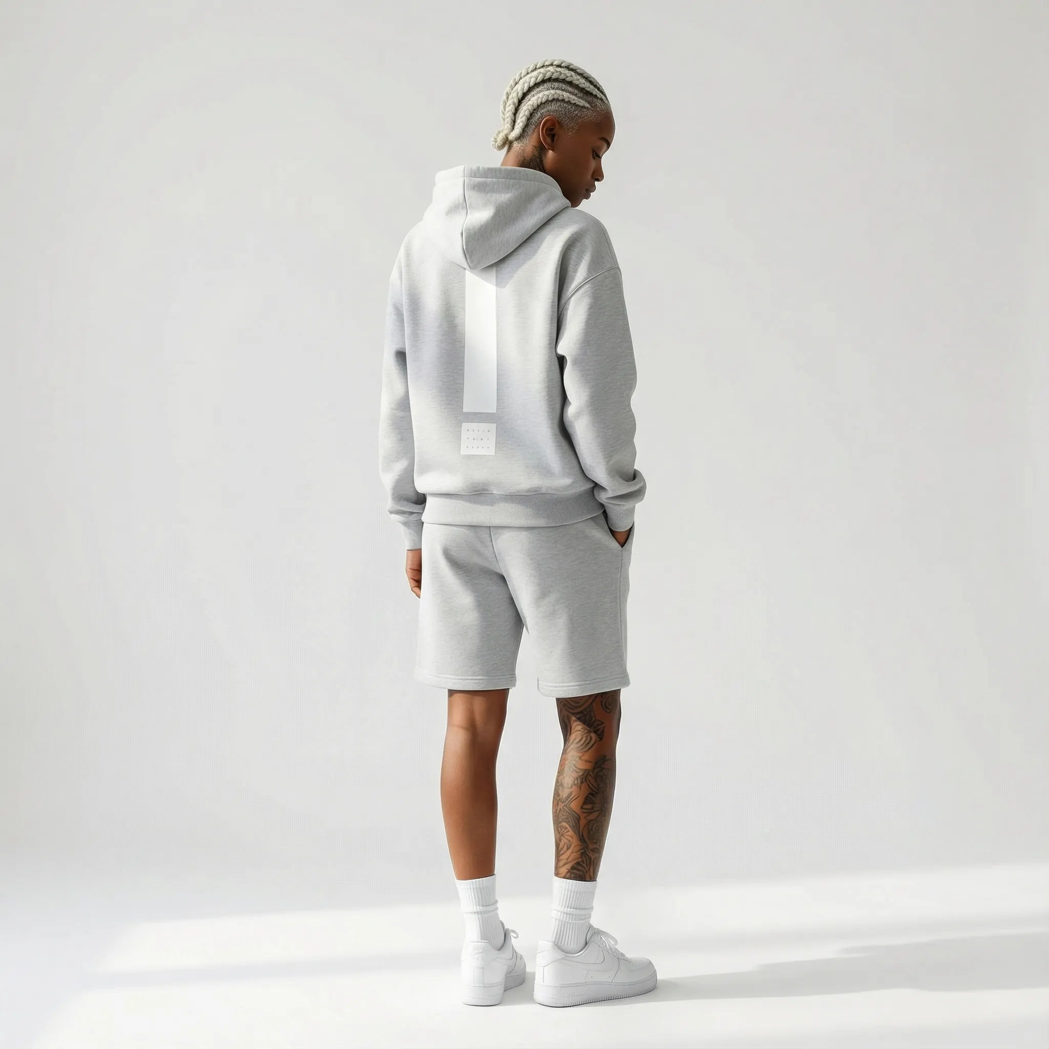 Person wearing a gray JAYTEE hoodie and shorts set on a white background