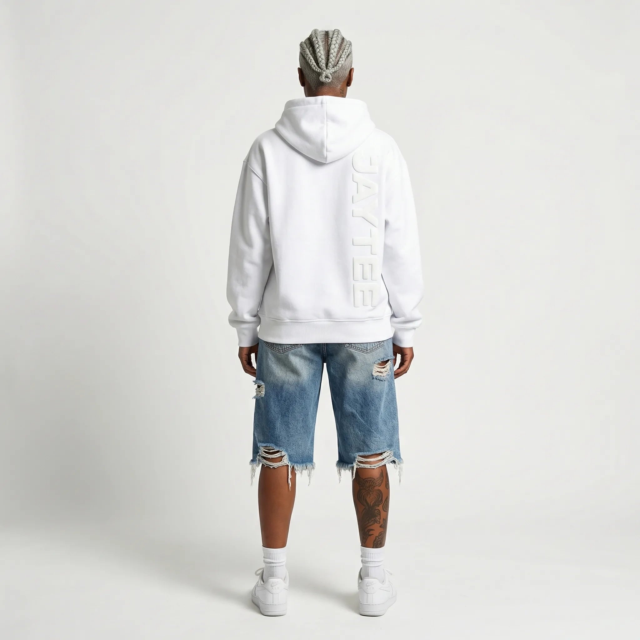 Person wearing a white JAYTEE hoodie with a brand logo on the back, standing against a plain background.