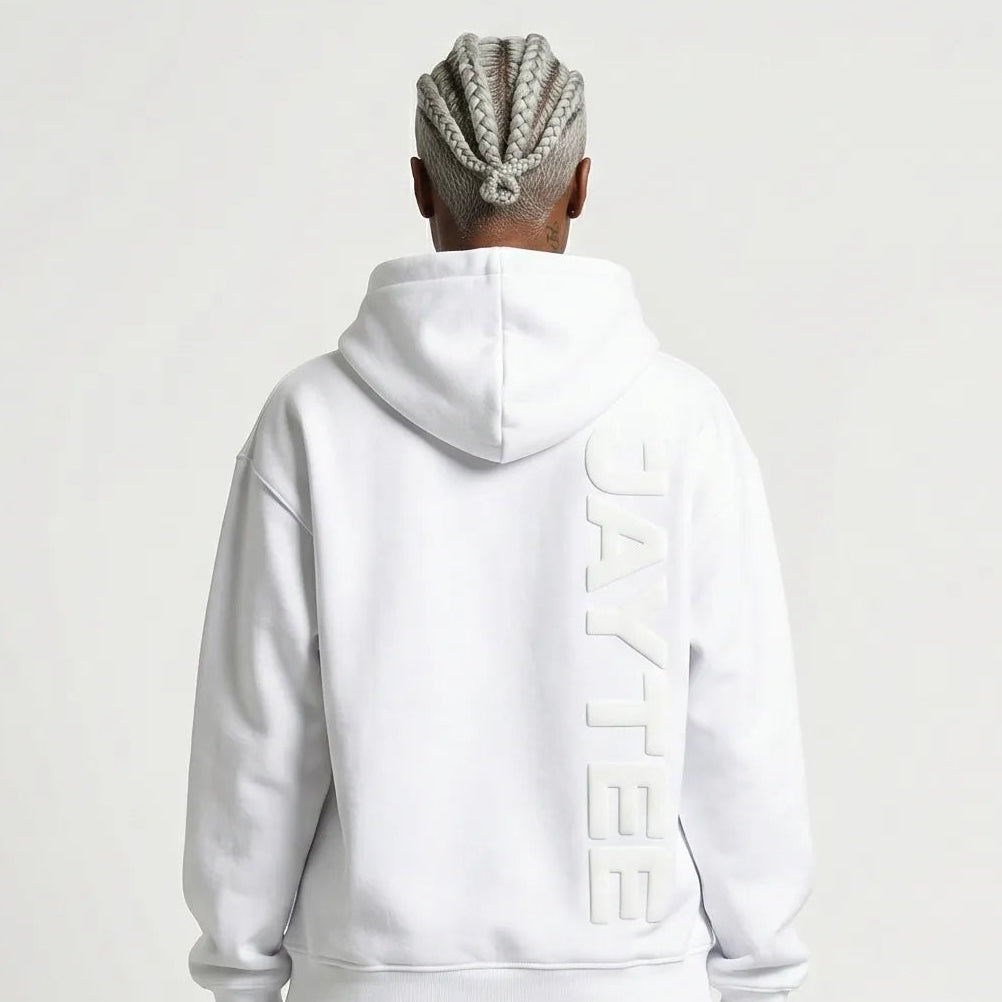 Person wearing a white JAYTEE hoodie with a brand logo on the back, standing against a plain background.