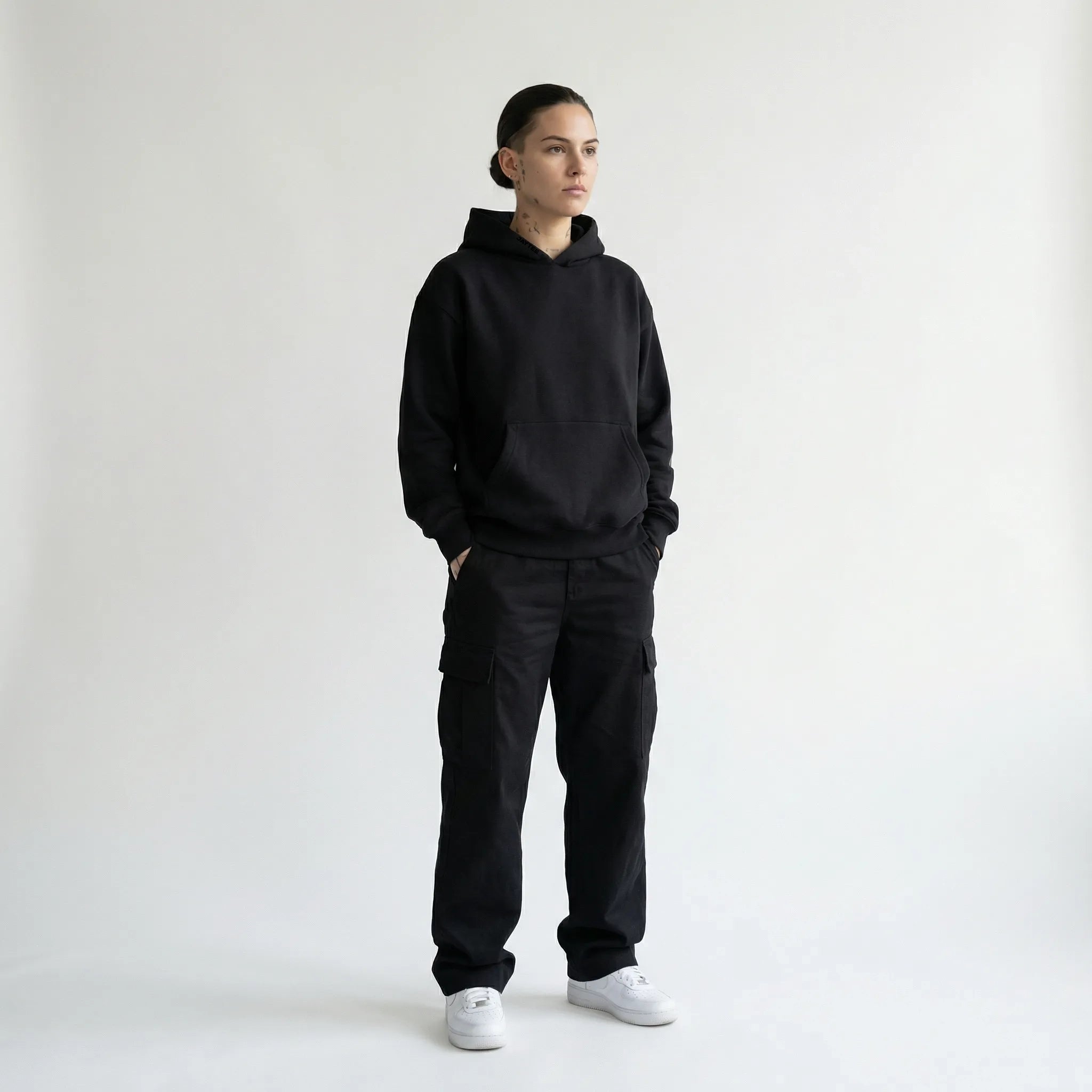 Person wearing a black JAYTEE hoodie and black pants on a white background