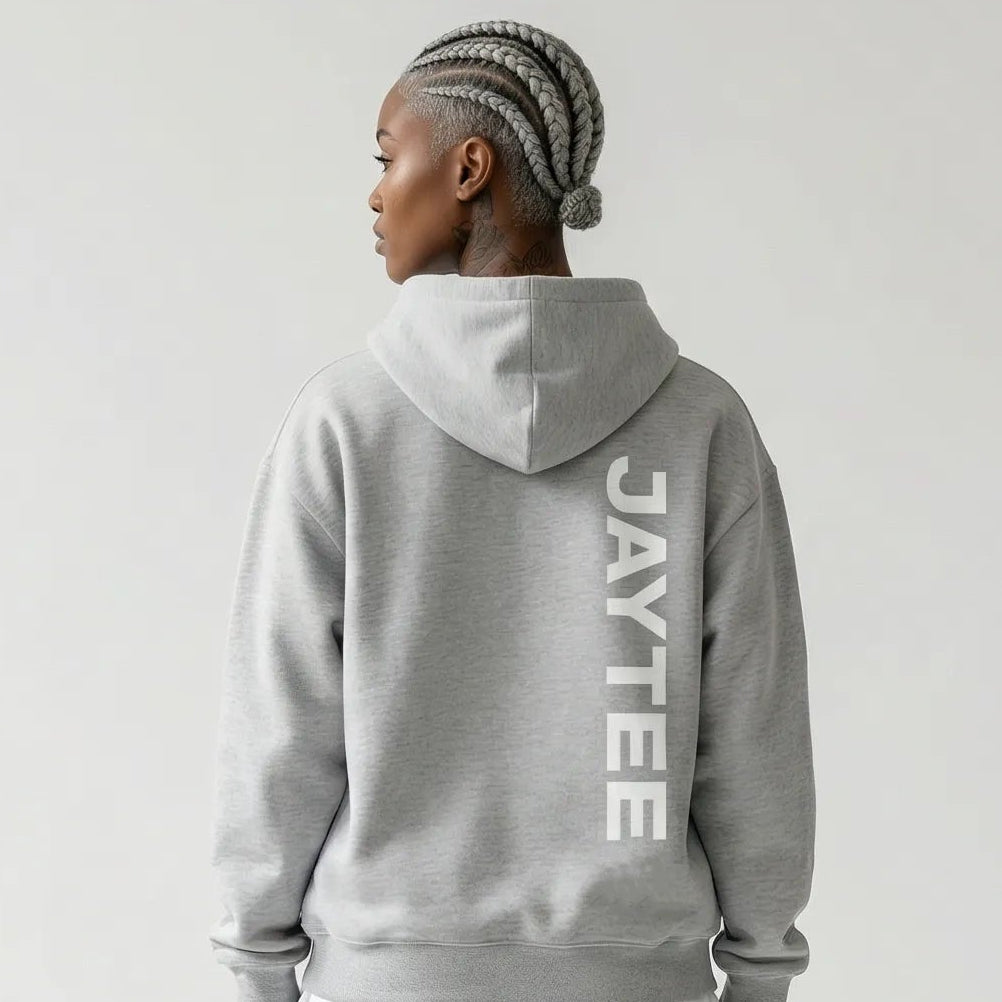Person wearing a gray JAYTEE hoodie and pants on a white background