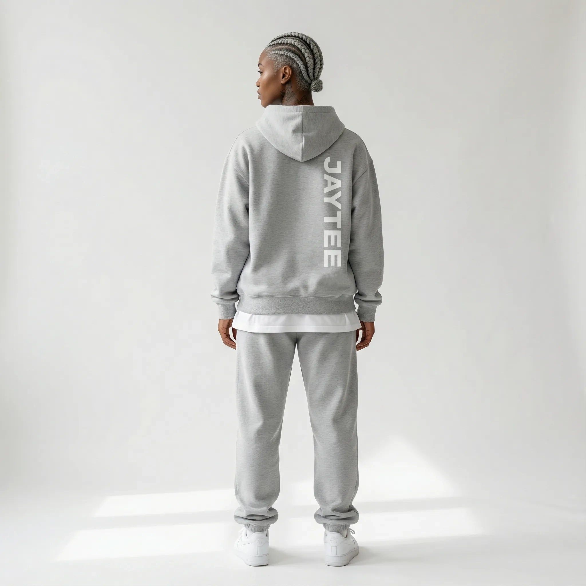 Person wearing a gray JAYTEE hoodie and pants on a white background