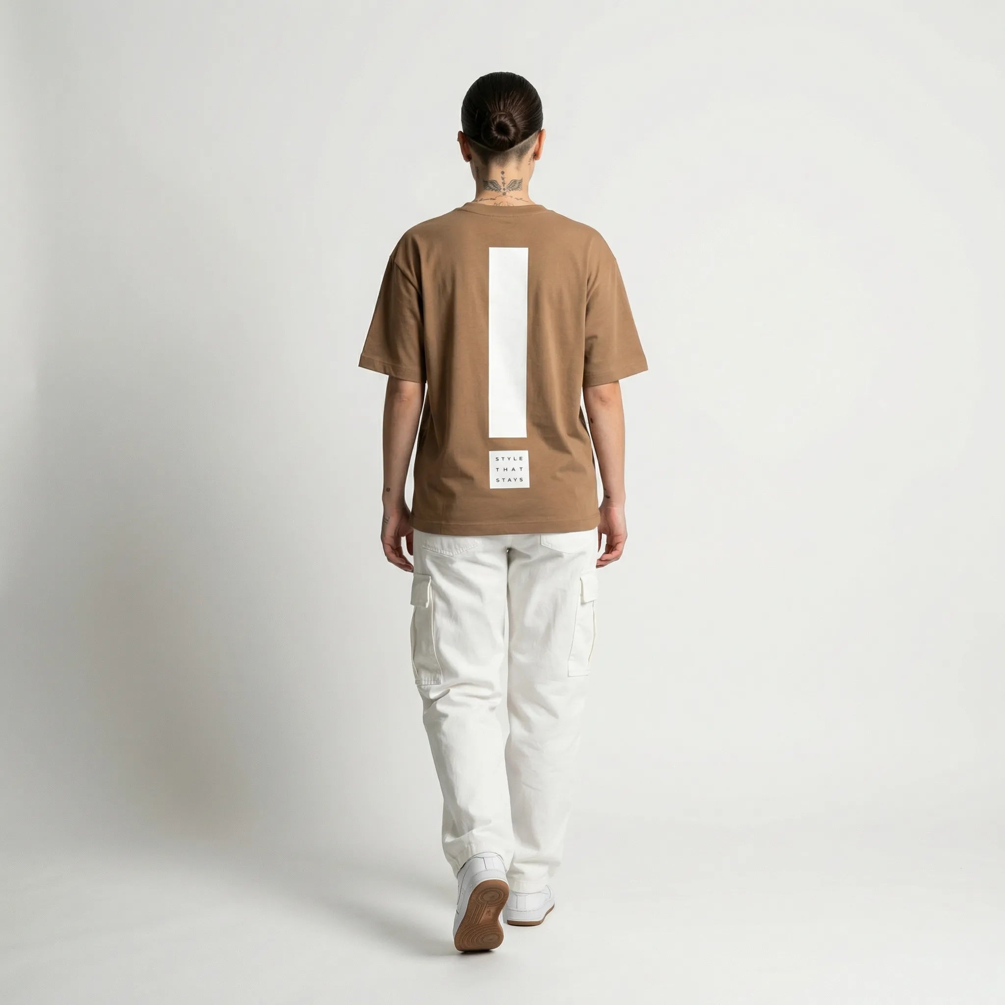 Person wearing a toffee JAYTEE t-shirt with a white logo on a plain background