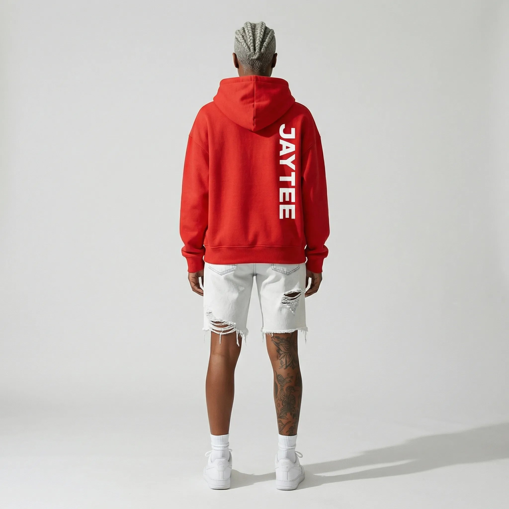 Person wearing a red hoodie with 'JAYTEE' branding on the back, standing against a plain background.