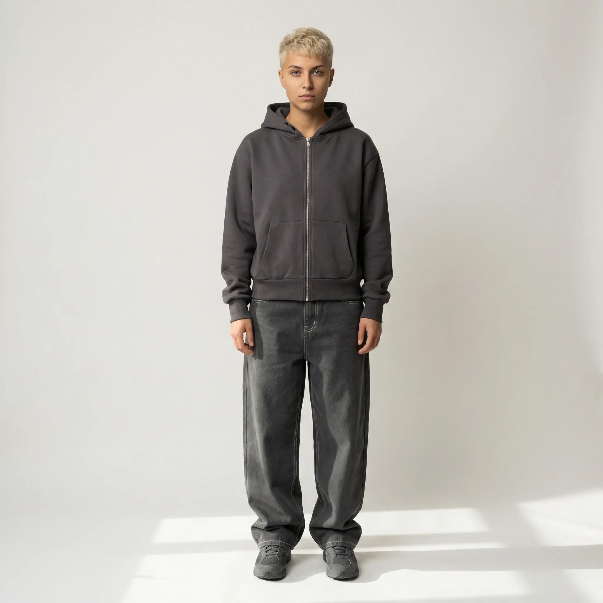 Person wearing a gray hoodie and pants on a white background