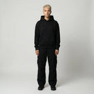 Person wearing a black hoodie and pants on a white background