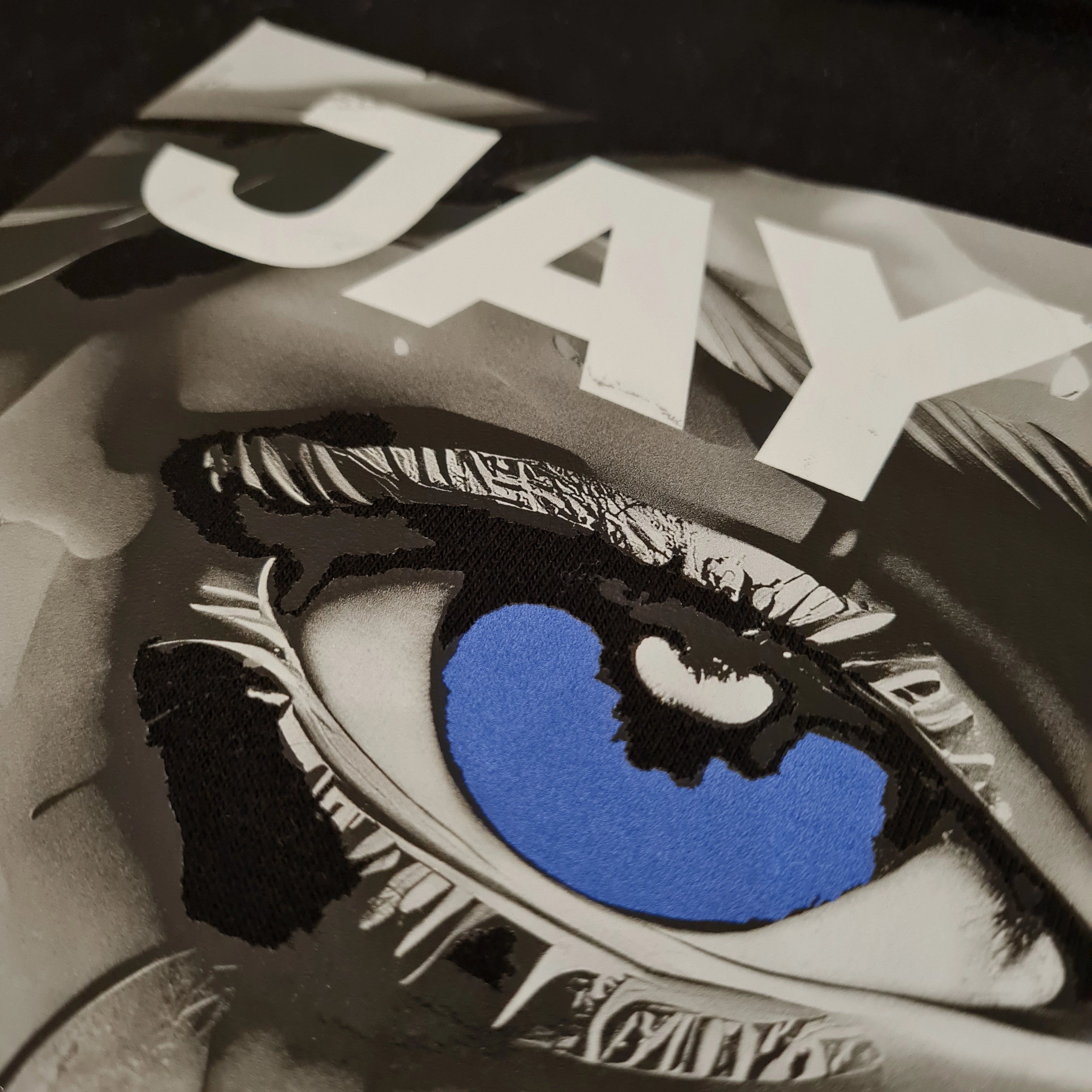 Close-up of a graphic t-shirt with a blue eye design and 'JAX' text.