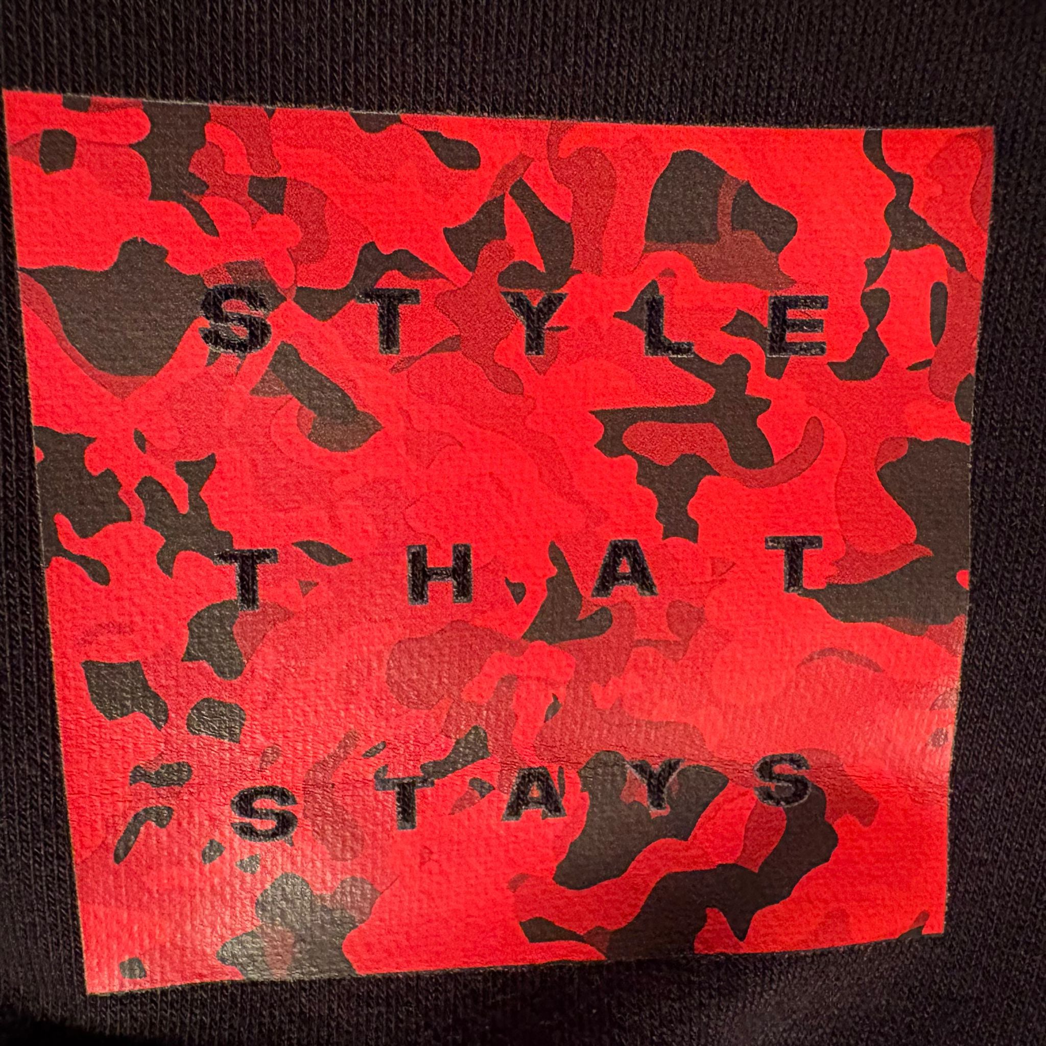 Red camouflage patch with black text on a black background