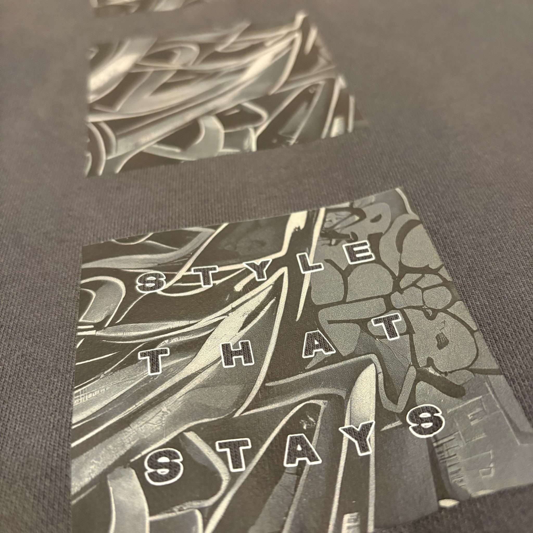 Close-up of a black t-shirt with graphic design and text on a dark background