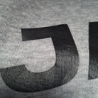 Close-up of a textured gray fabric with a black letter 'P' on a gray background