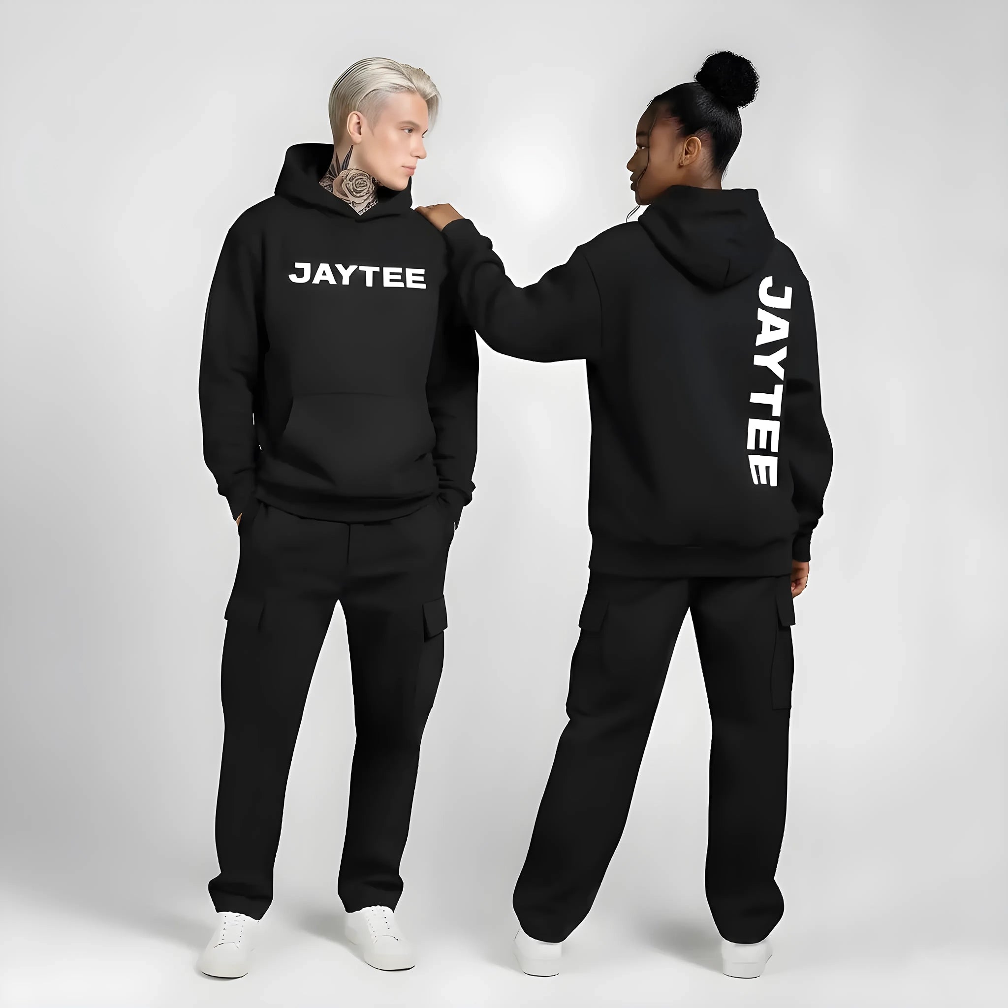 Two people wearing black 'JAYTEE' hoodies and pants on a white background