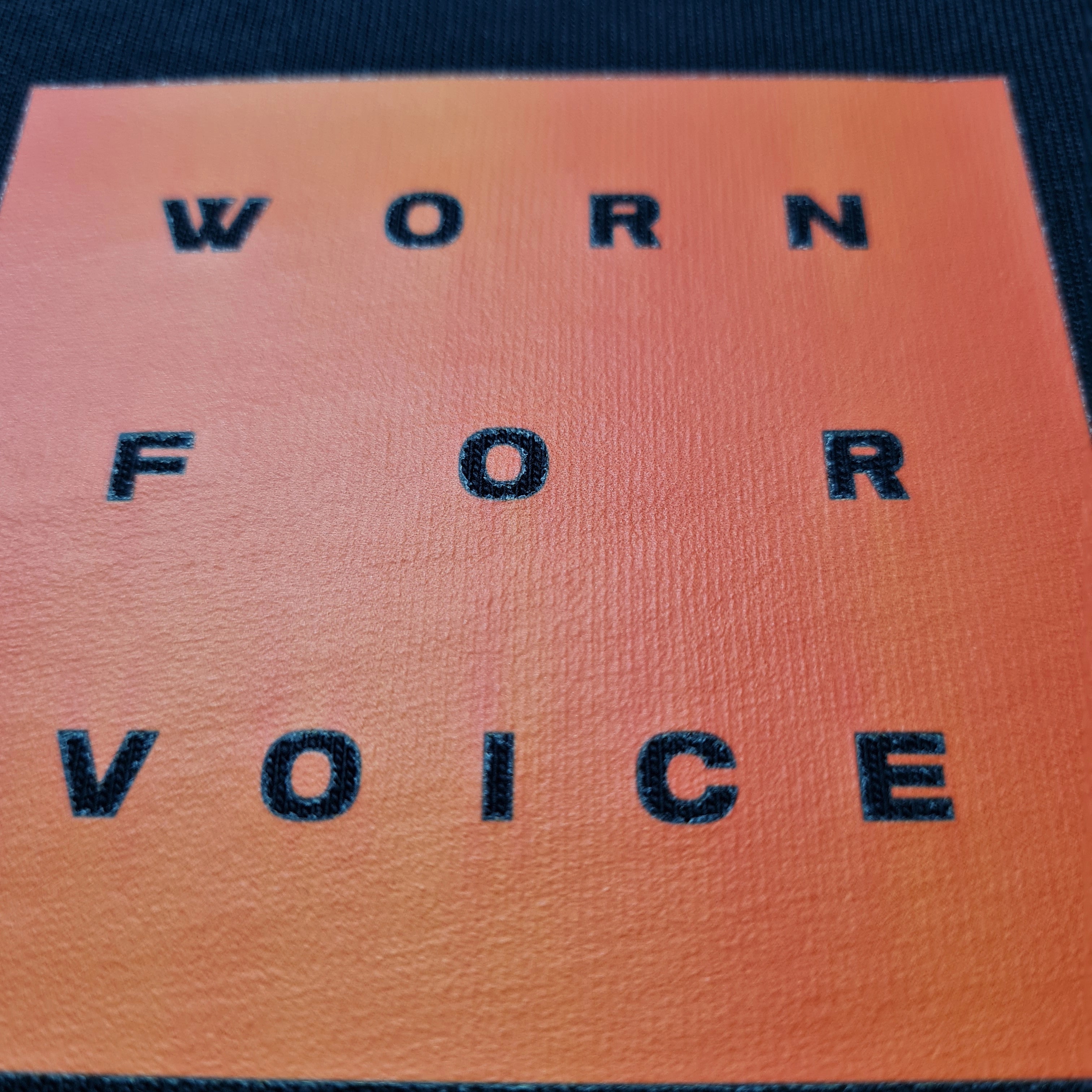 Text 'WORN FOR VOICE' on a textured surface with a gradient background