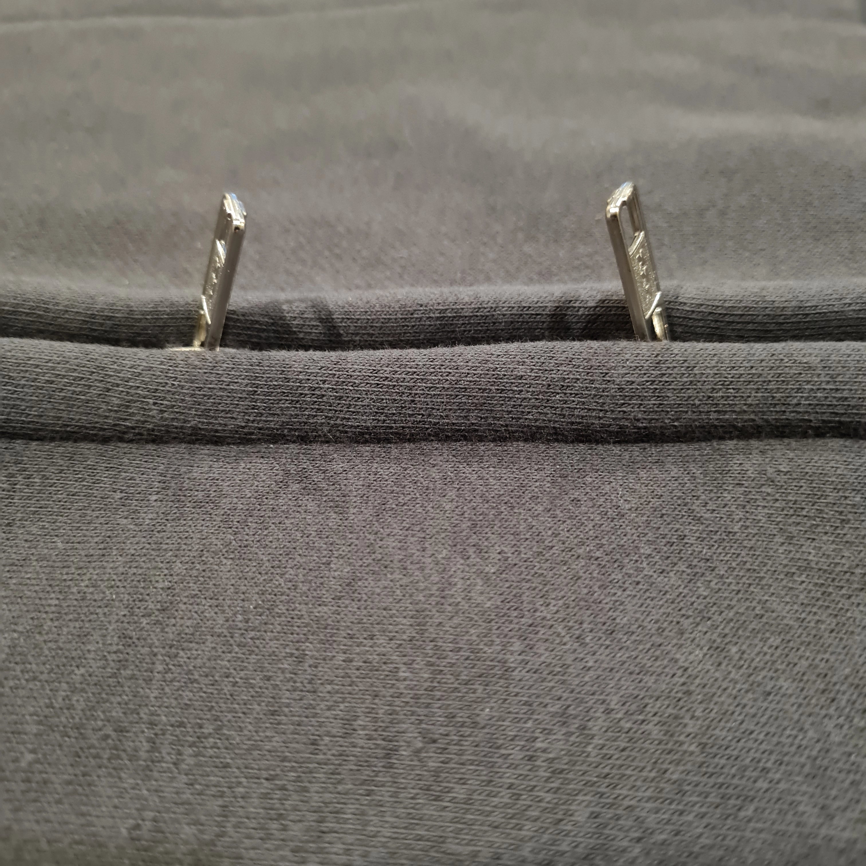 Close-up of gray fabric with metal grommets on a textured background