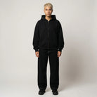 Person wearing a black hoodie and pants on a plain background