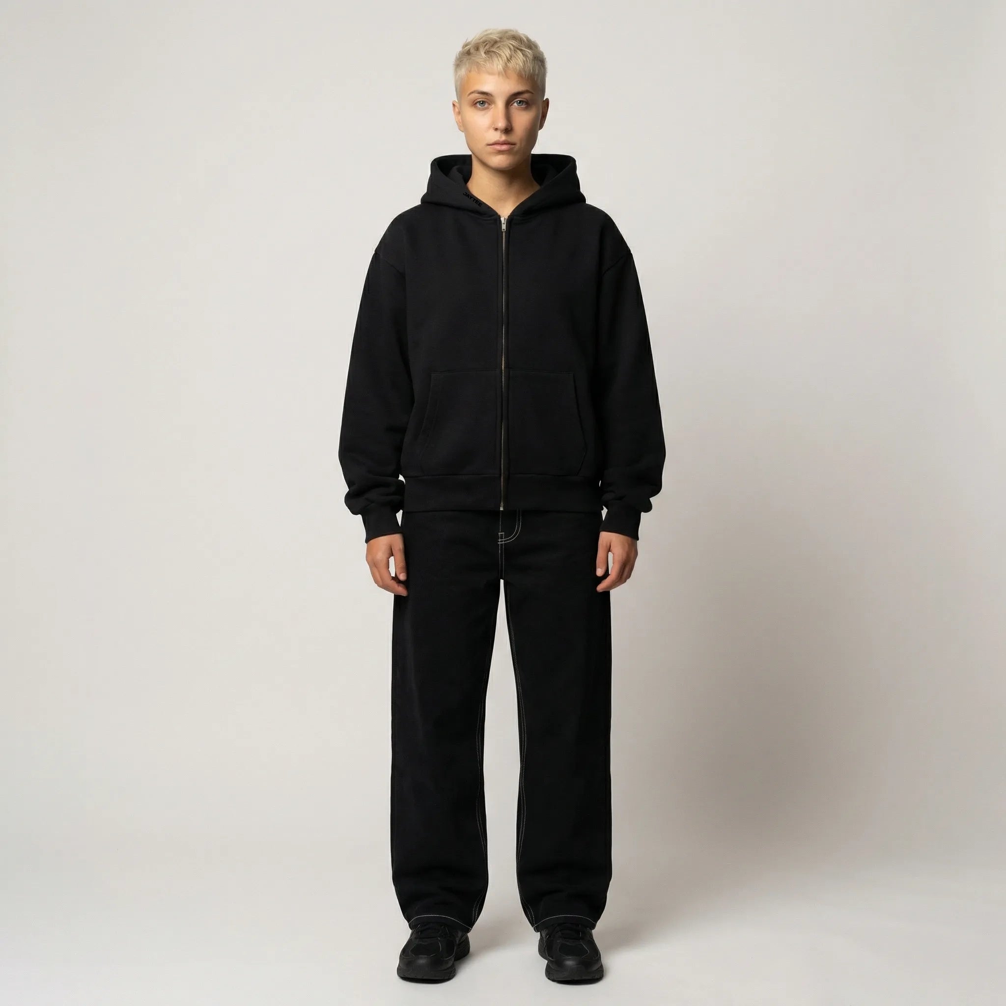 Person wearing a black hoodie and pants on a plain background