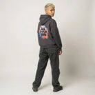 Person wearing a black hoodie with a colorful paw print design on the back, standing against a plain background.