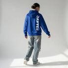 Person wearing a blue hoodie with 'JAYTEE' branding, standing on a light gray background