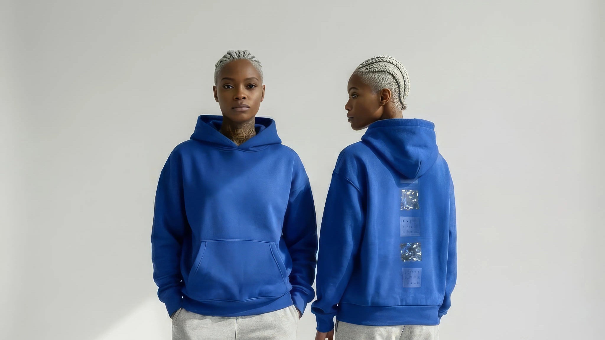 Person wearing a blue JAYTEE hoodie and gray pants, standing against a white background