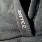 Close-up of a black hoodie with 'JAYTEE' branding.