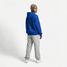 Person wearing a blue JAYTEE hoodie and gray pants on a white background