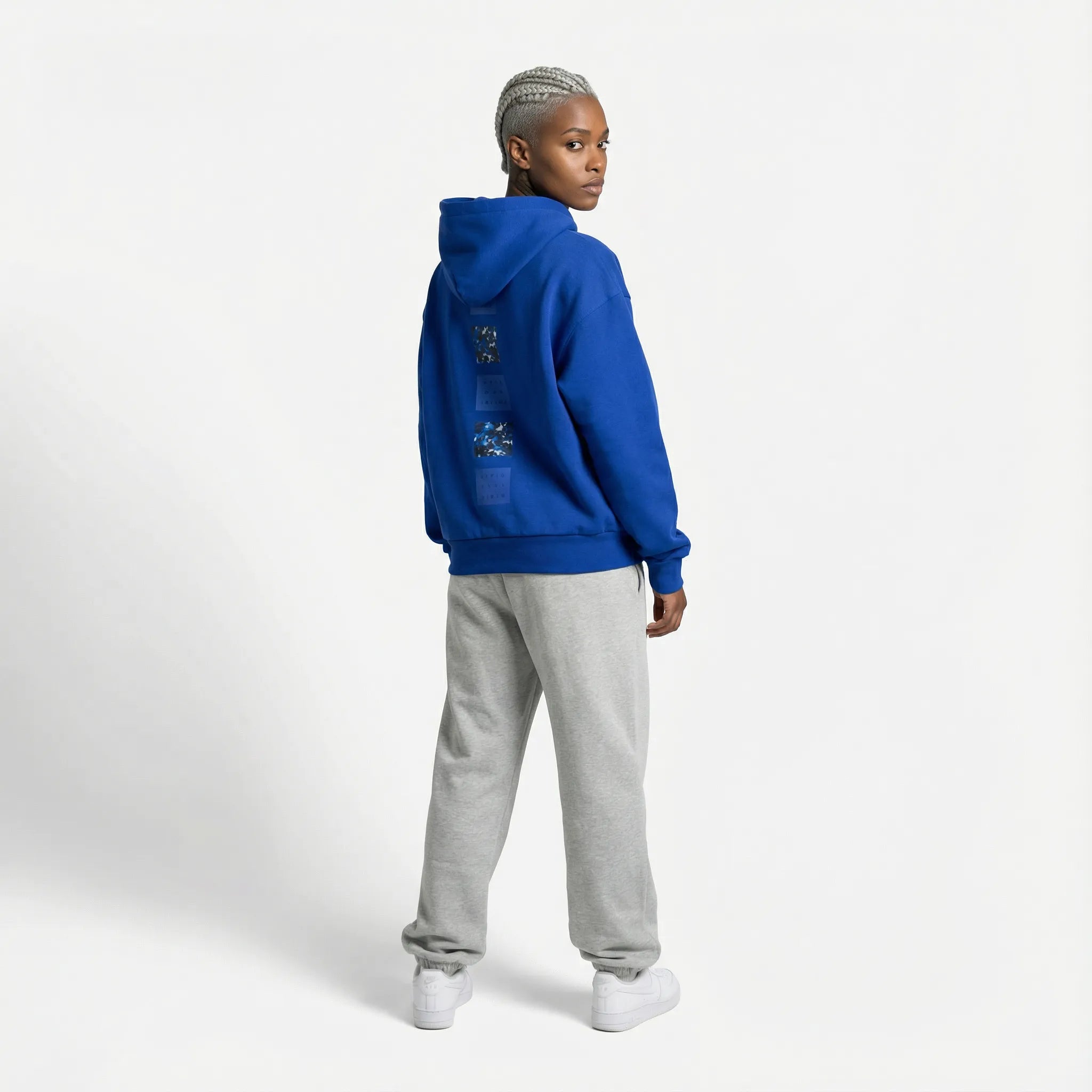 Person wearing a blue JAYTEE hoodie and gray pants on a white background