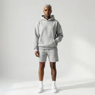 Person wearing a gray JAYTEE  hoodie and shorts set on a white background