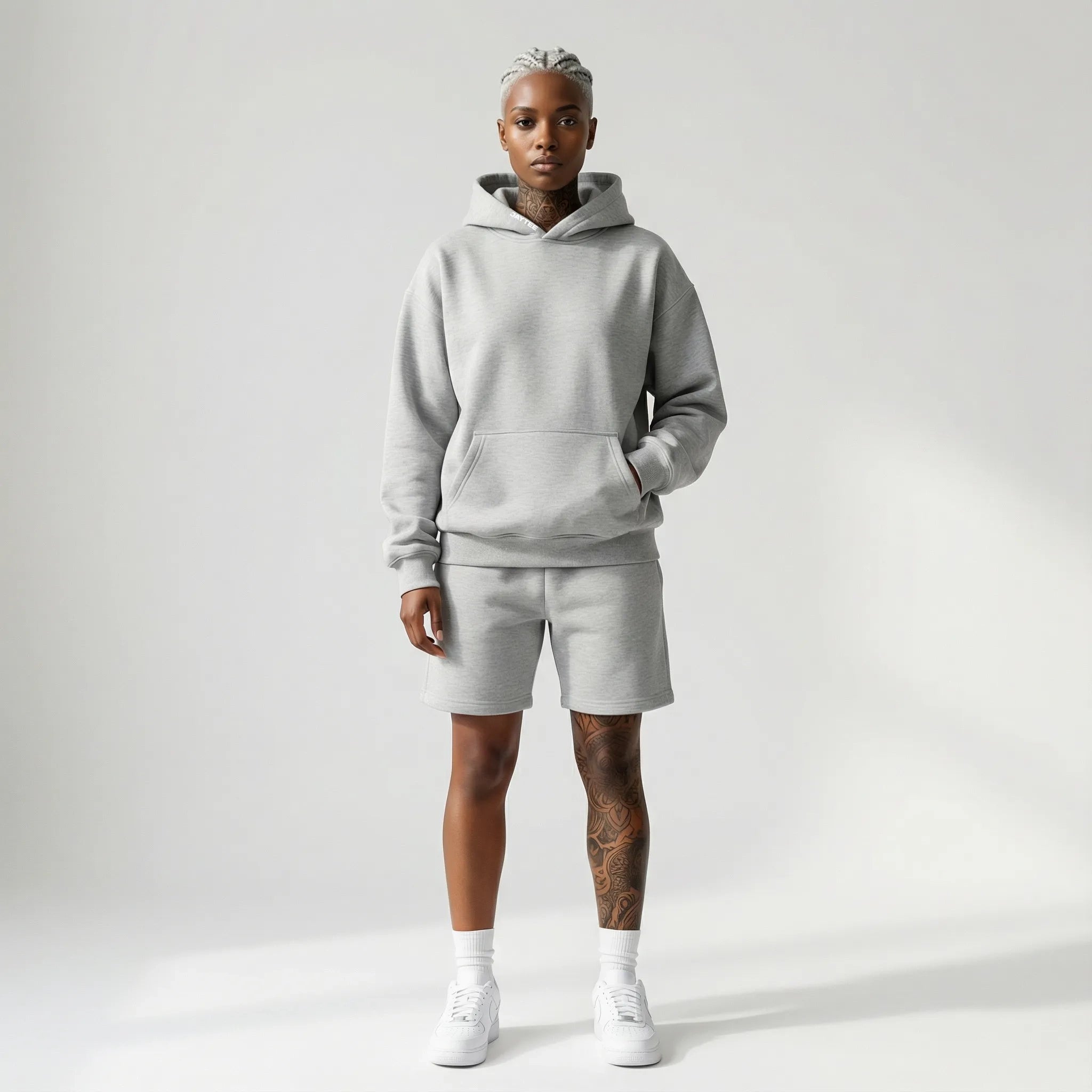 Person wearing a gray JAYTEE  hoodie and shorts set on a white background