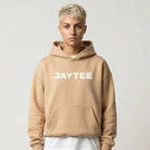 Person wearing a sand JAYTEE hoodie  logo on a white background