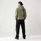 Person wearing a green hoodie with JAYTEE branding on the back, standing against a white background.