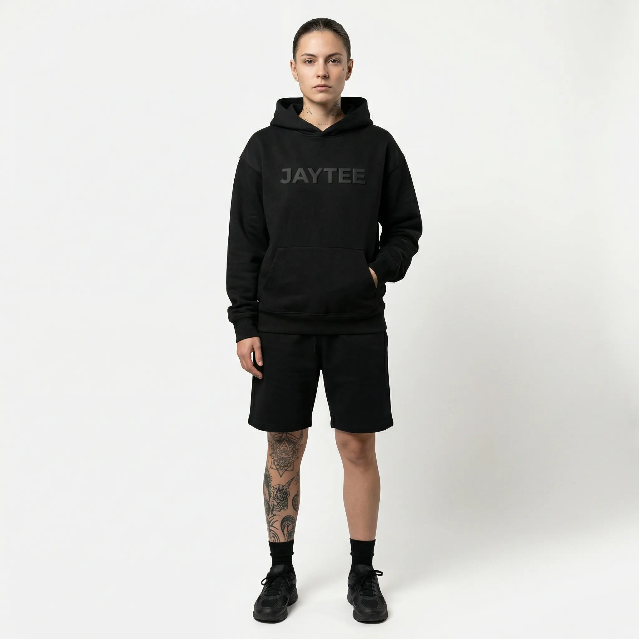 Person wearing a black hoodie with JAYTEE branding on a white background