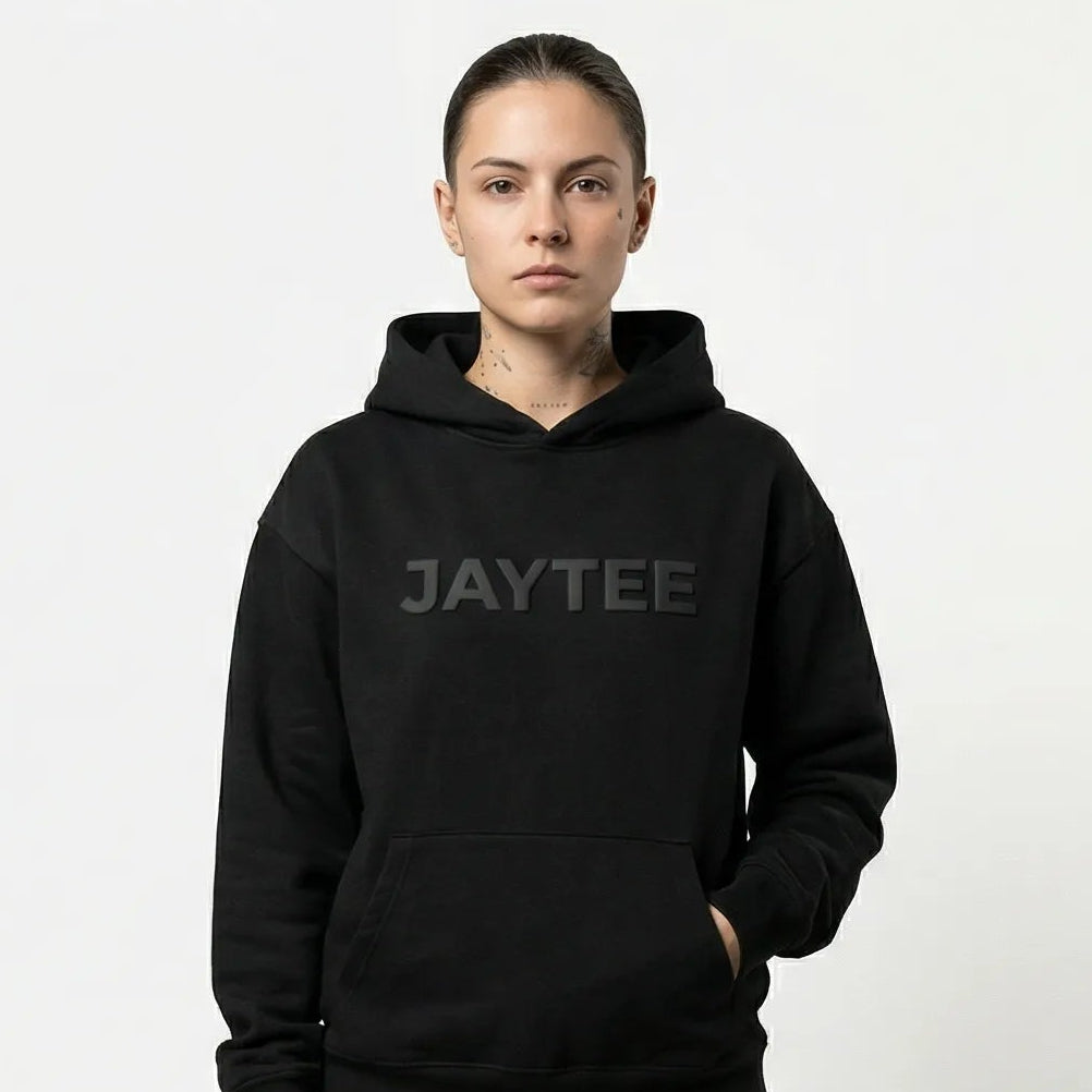 Person wearing a black hoodie with JAYTEE branding on a white background