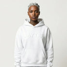 Person wearing a white JAYTEE hoodie and ripped jeans on a plain background