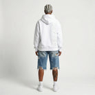 Person wearing a white JAYTEE hoodie with a brand logo on the back, standing against a plain background.