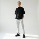 Person wearing a black t-shirt and gray sweatpants with JAYTEE branding on a white background