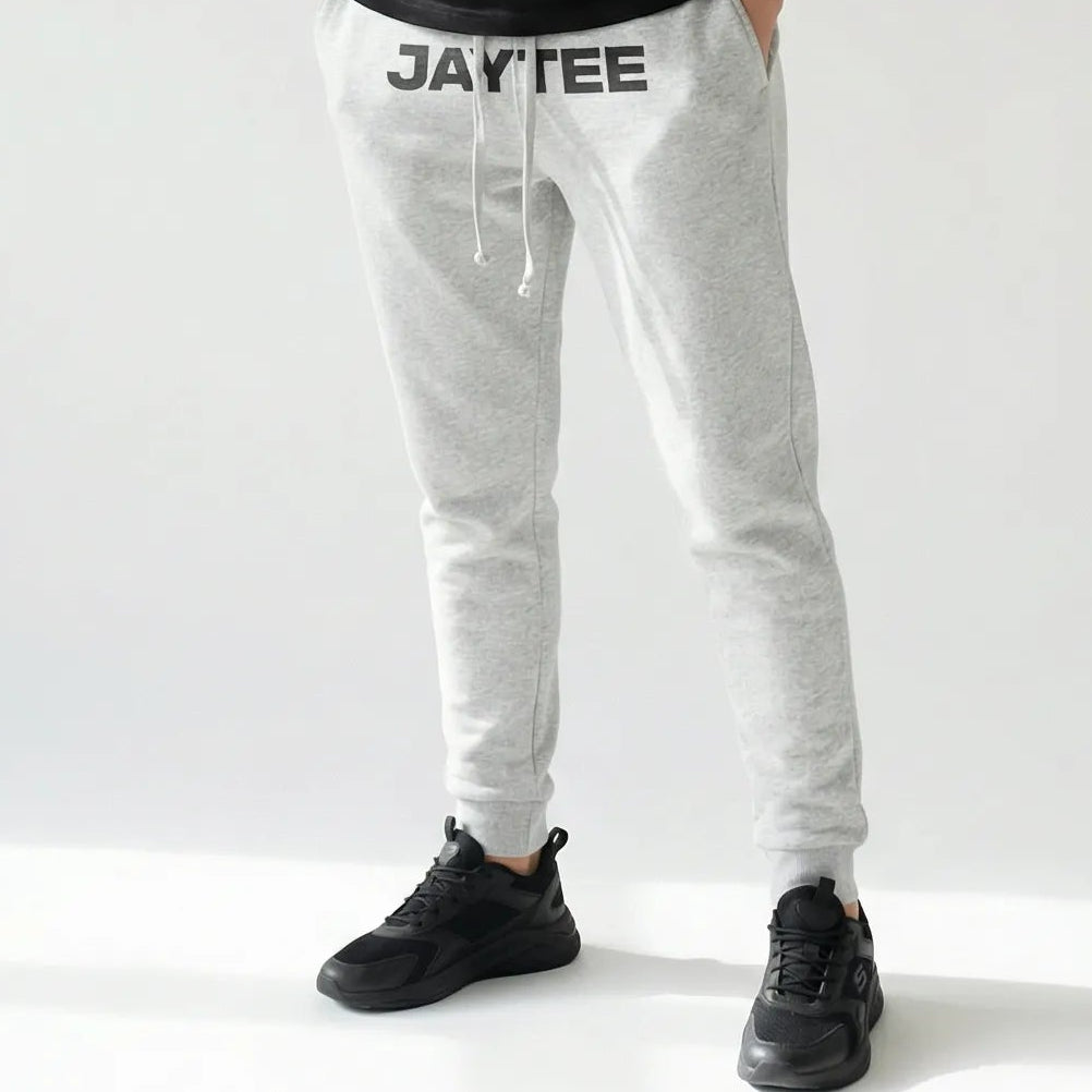 Person wearing a black t-shirt and gray sweatpants with JAYTEE branding on a white background