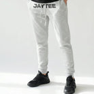 Person wearing a black t-shirt and gray sweatpants with JAYTEE branding on a white background
