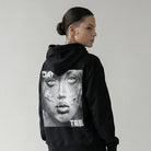 Person wearing a black JAYTEE hoodie with a graphic design on the back against a plain background