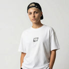 Person wearing a white JAYTEE  t-shirt, black pants, and a cap on a plain background