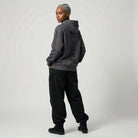Person wearing a dark gray  JAYTEE hoodie and black pants on a light gray background