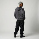 Person wearing a gray  JAYTEE hoodie with text on the back and black pants against a white background