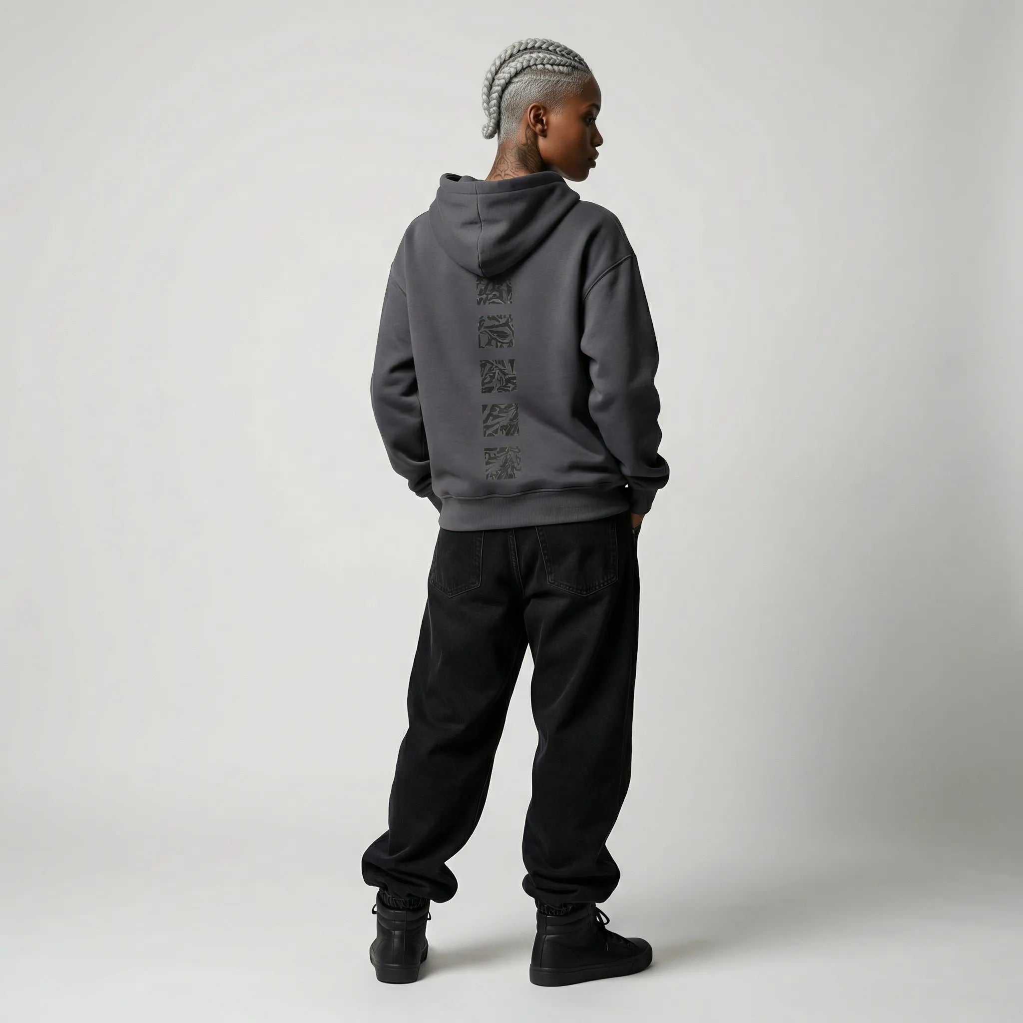 Person wearing a gray  JAYTEE hoodie with text on the back and black pants against a white background