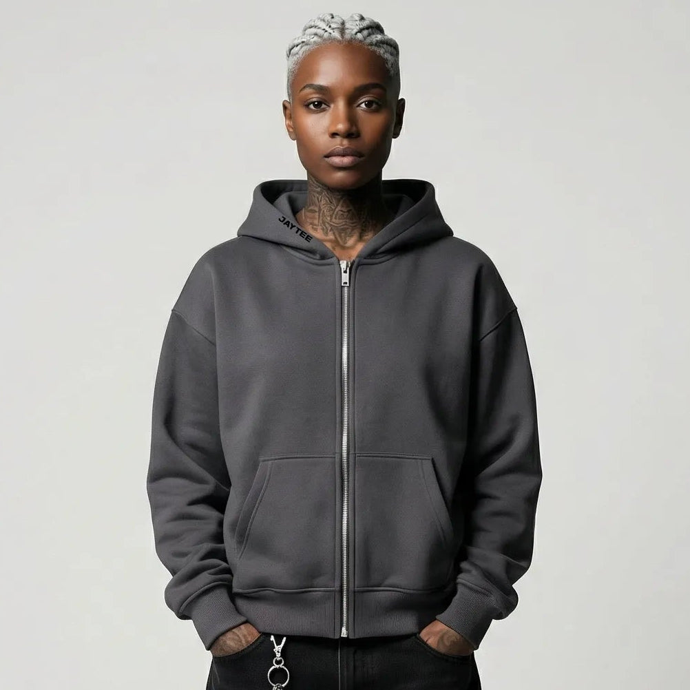 Person wearing a gray  JAYTEE hoodie and black pants on a plain background