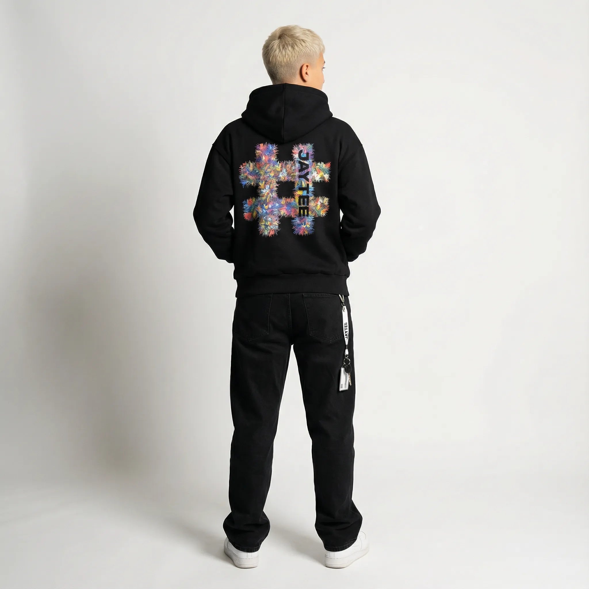 Person wearing a black JAYTEE hoodie with a colorful hashtag design on the back, standing against a plain background.