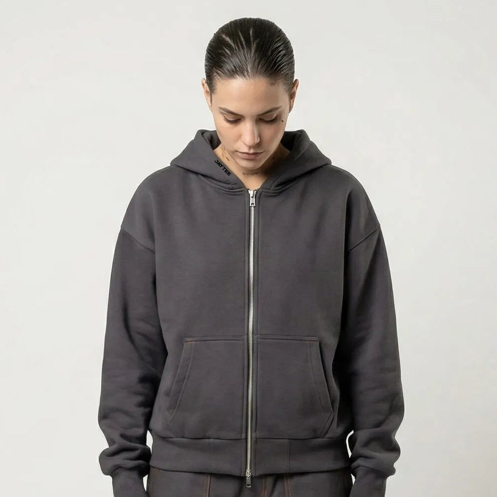 Person wearing a dark gray JAYTEE hoodie and cargo pants on a white background