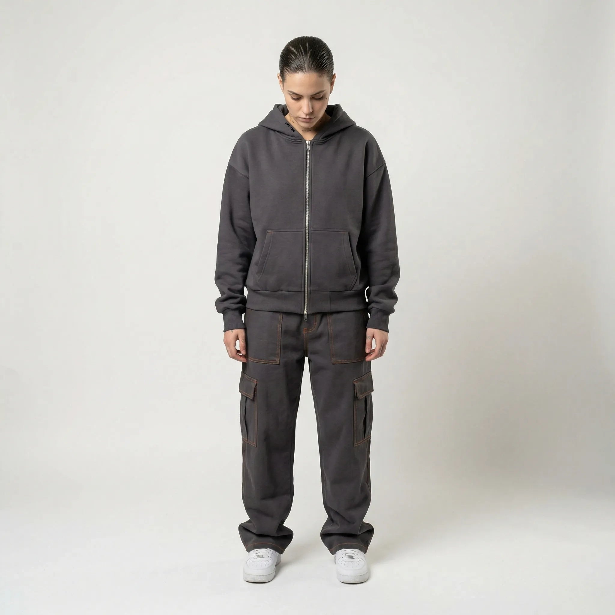 Person wearing a dark gray JAYTEE hoodie and cargo pants on a white background