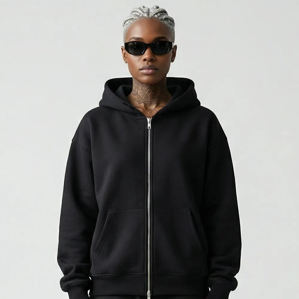 Person wearing a black JAYTEE hoodie and pants holding a red and black patterned bandana on a white background