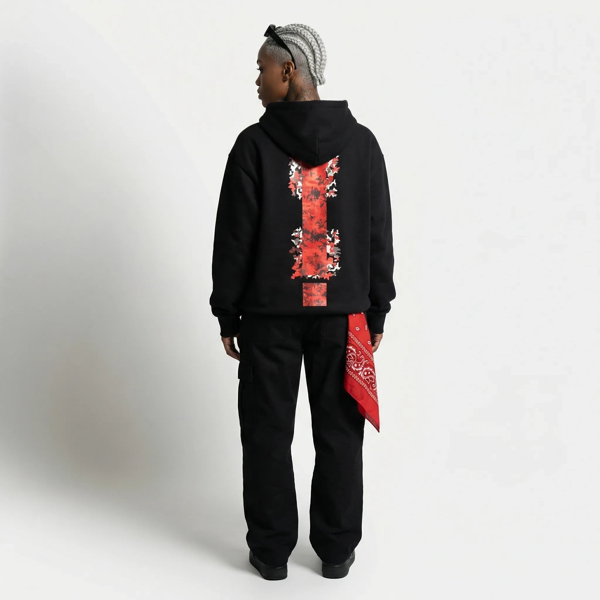 Person wearing a black  JAYTEE hoodie with red and white design on the back, standing against a plain background.